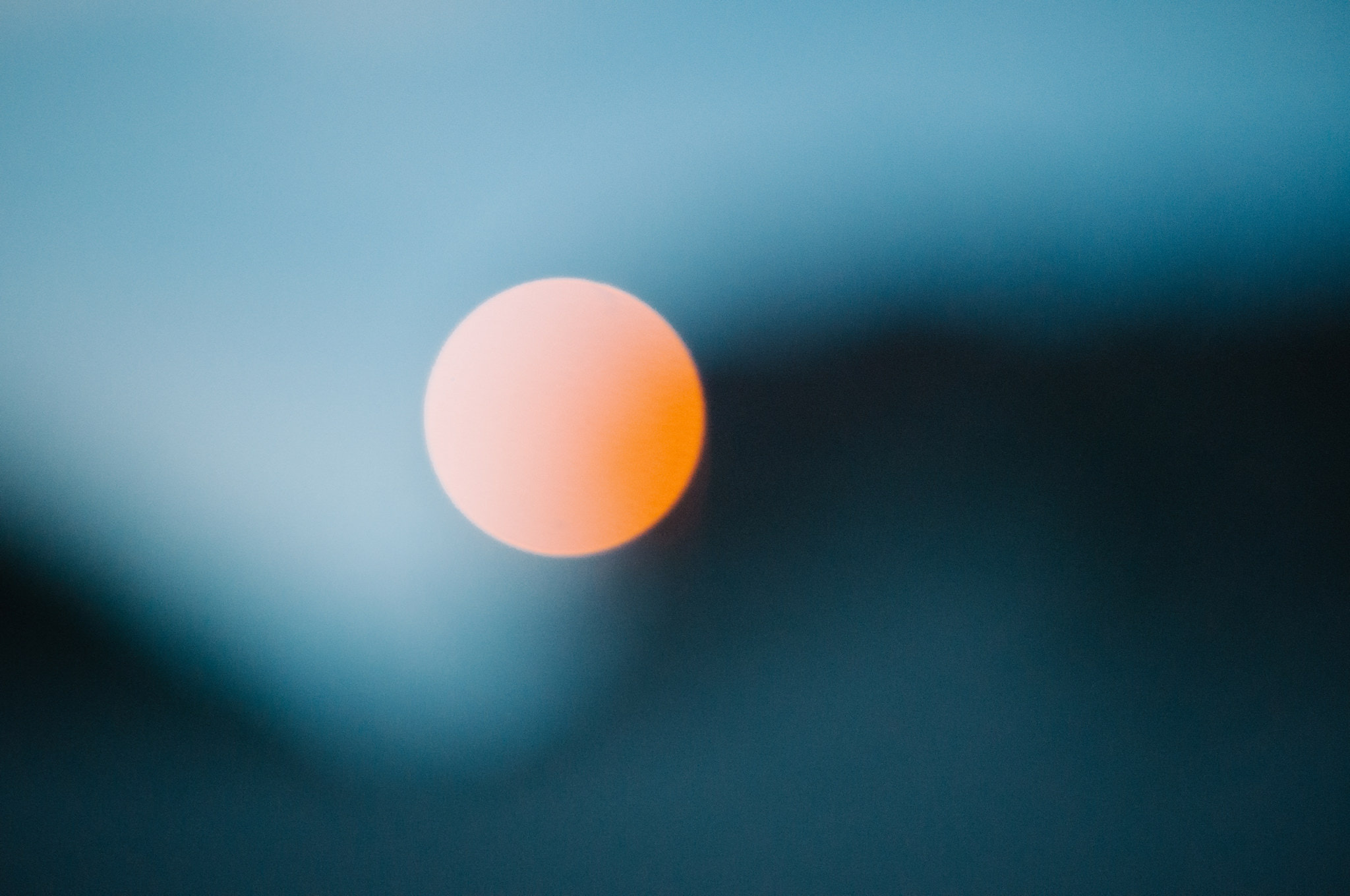 Orange sunset over dark mountain silhouette against blue sky