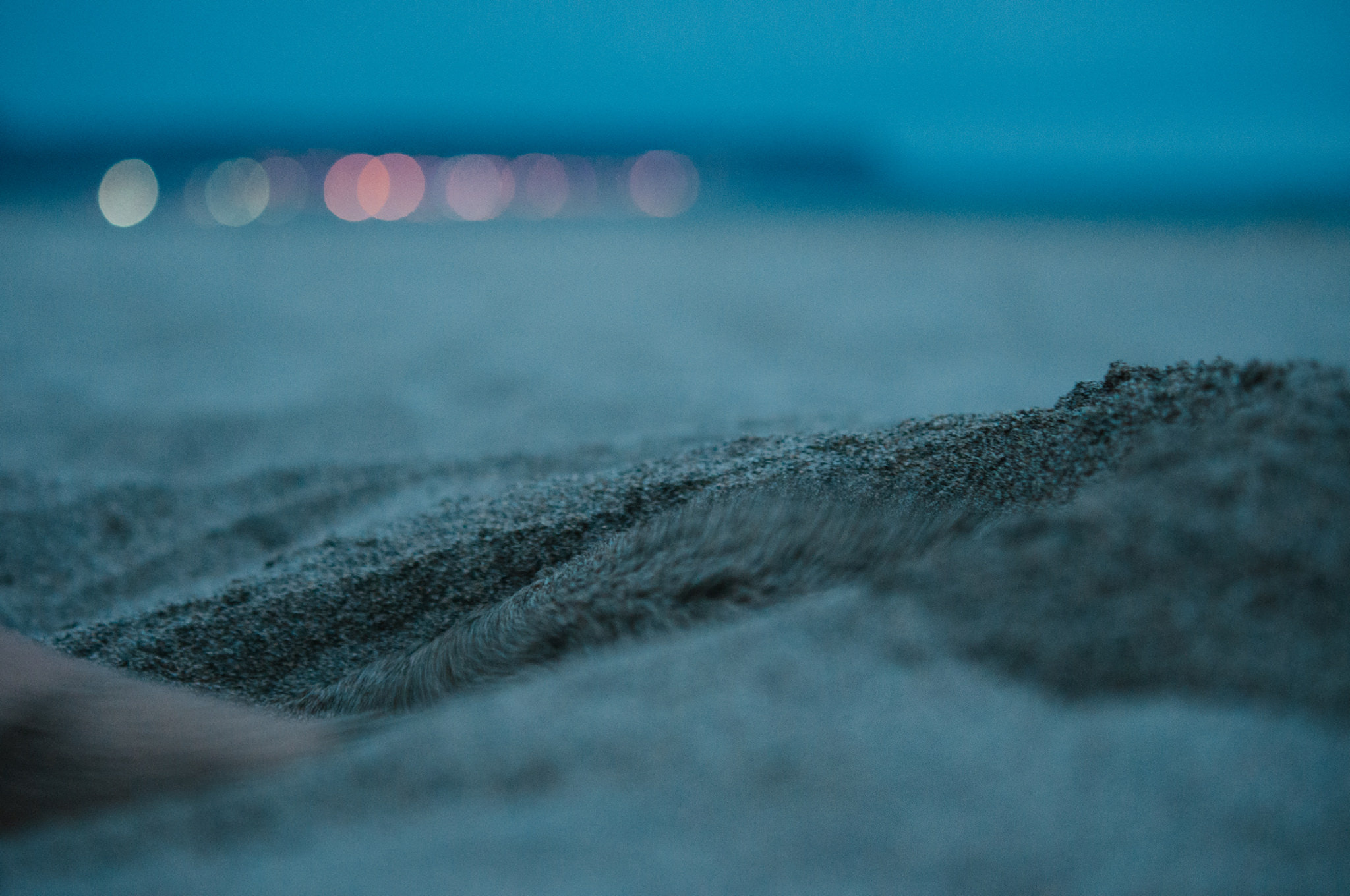 Close-up of sand textures at twilight with distant city lights
