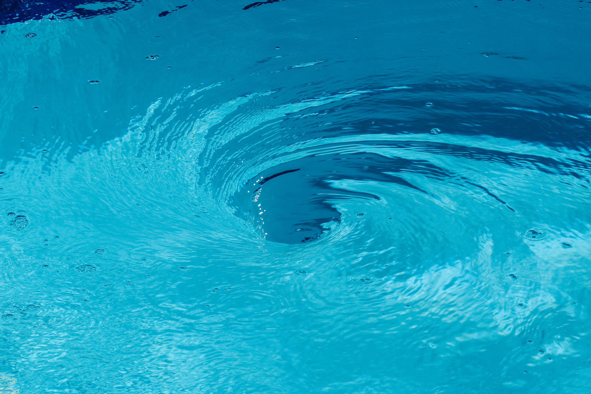 Vortex of swirling blue water forming a whirlpool