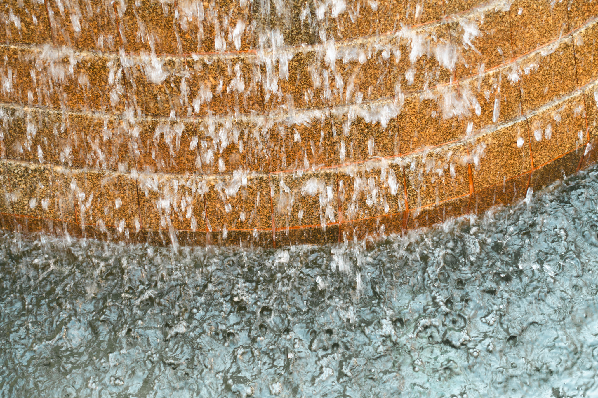 Water cascading down curved stone tiers into a rippling pool