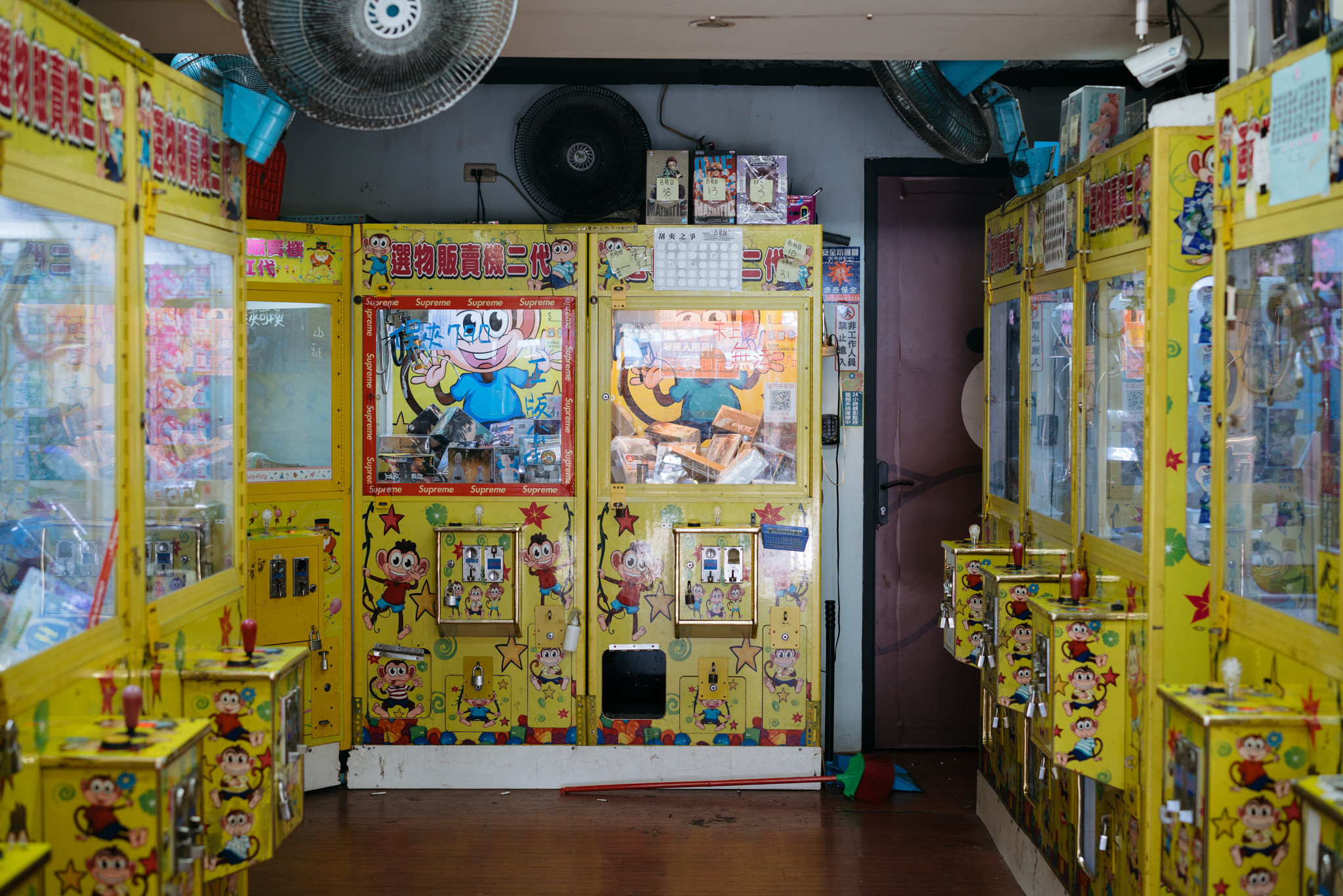 Row of yellow claw machines in an arcade filled with prizes