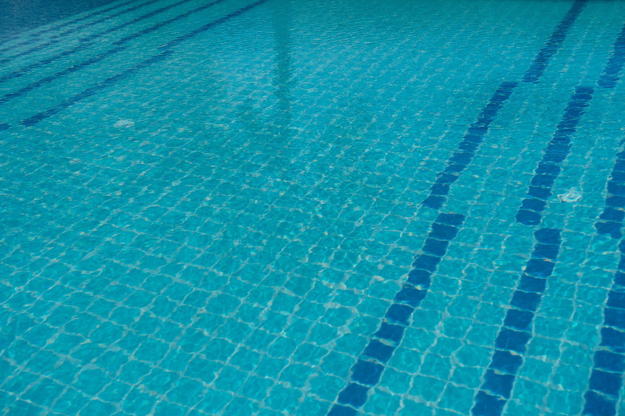 Close-up view of clear blue swimming pool water with tiled lane markers