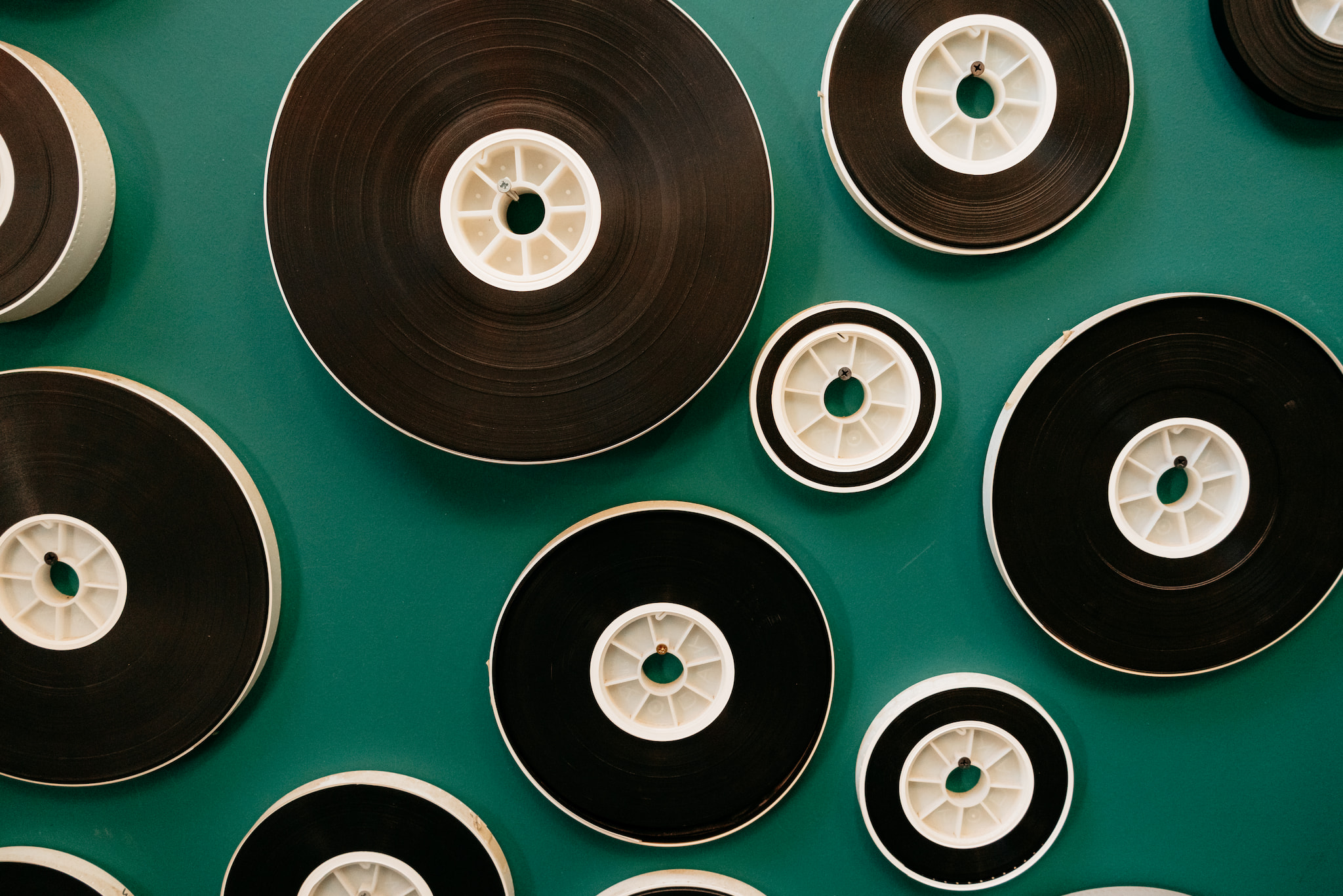 Various sizes of circular film reels mounted on a solid teal green wall.