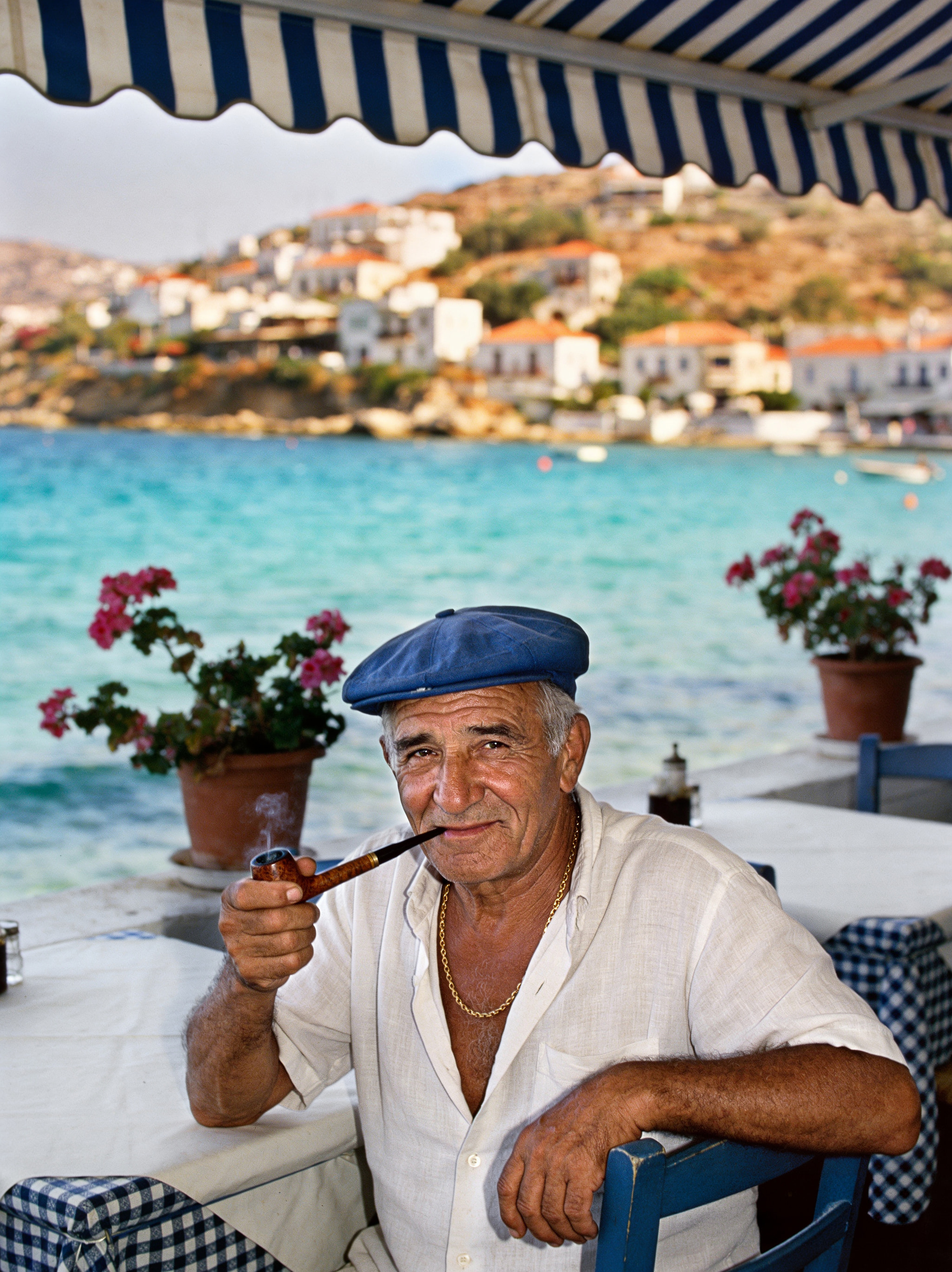 Elderly man smoking a pipe by the sea in Greece