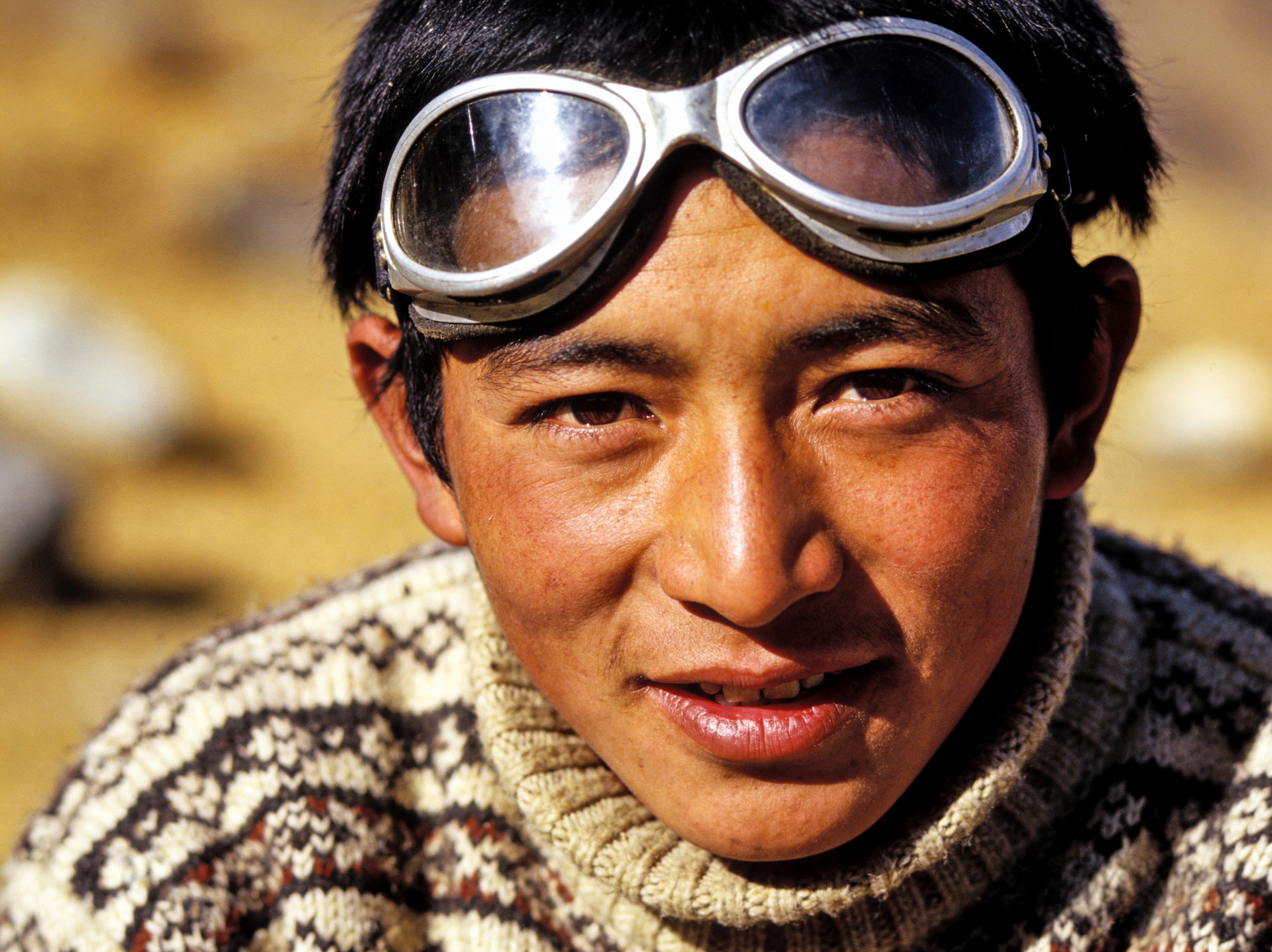 Close-up portrait of a man wearing protective goggles and a patterned wool sweater.