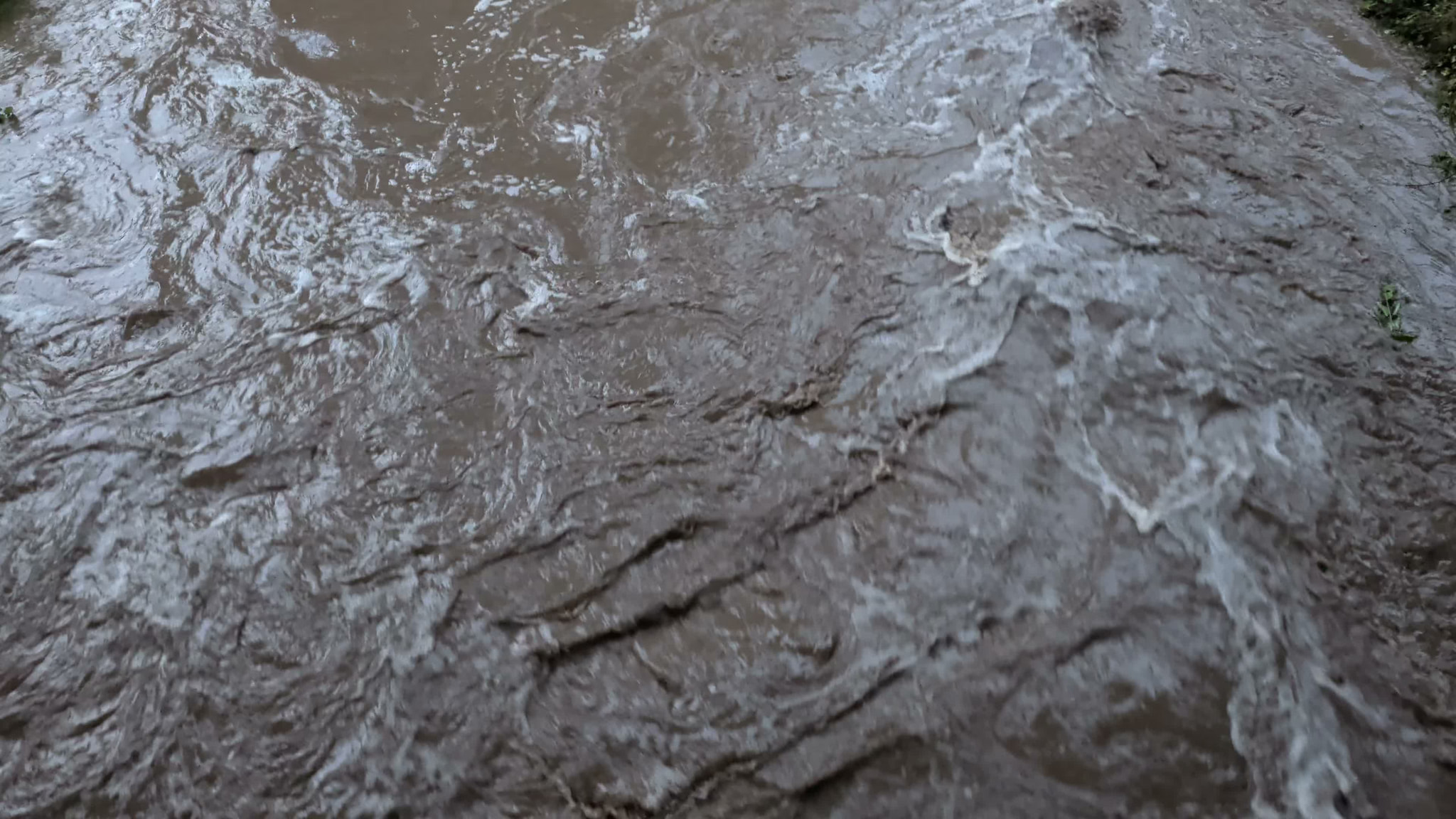 Swirling muddy water flowing rapidly in a stream