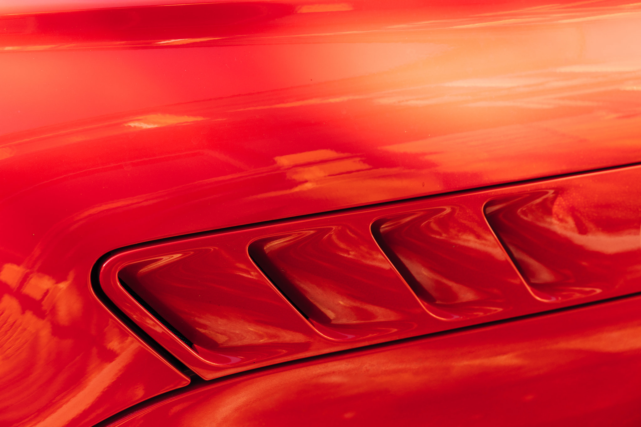 Close-up of bright red car body panel with air vents