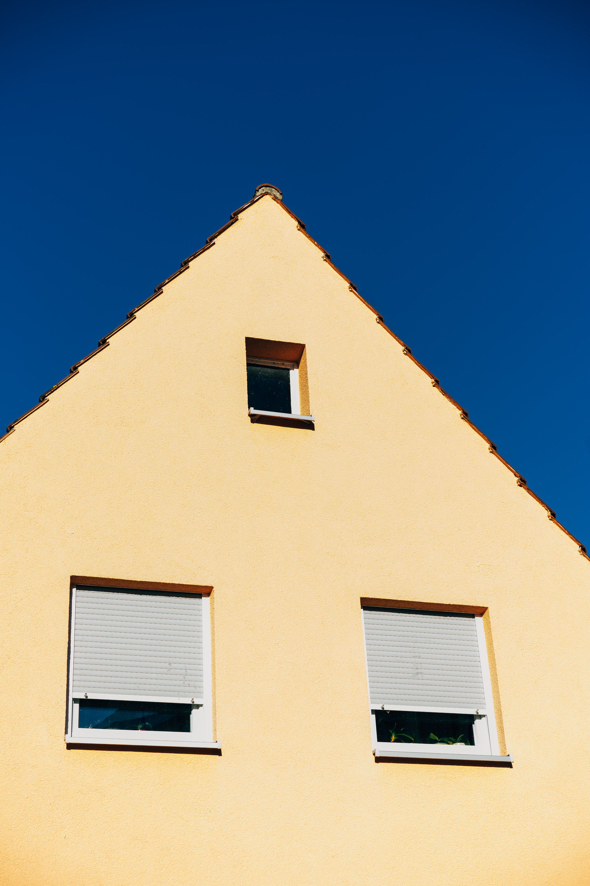 A yellow house gable against a deep blue sky
