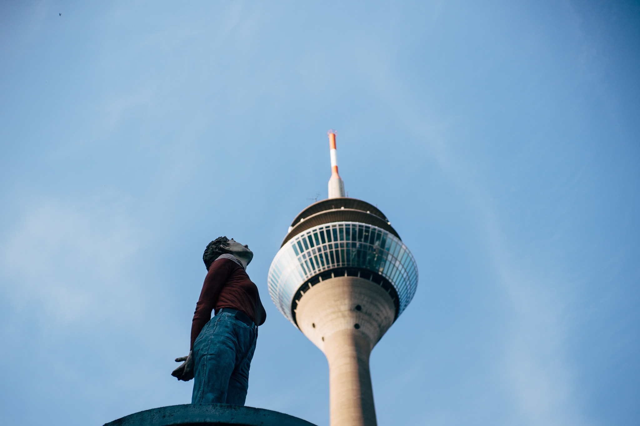 Person looking up at a tall telecommunications tower against a clear blue sky