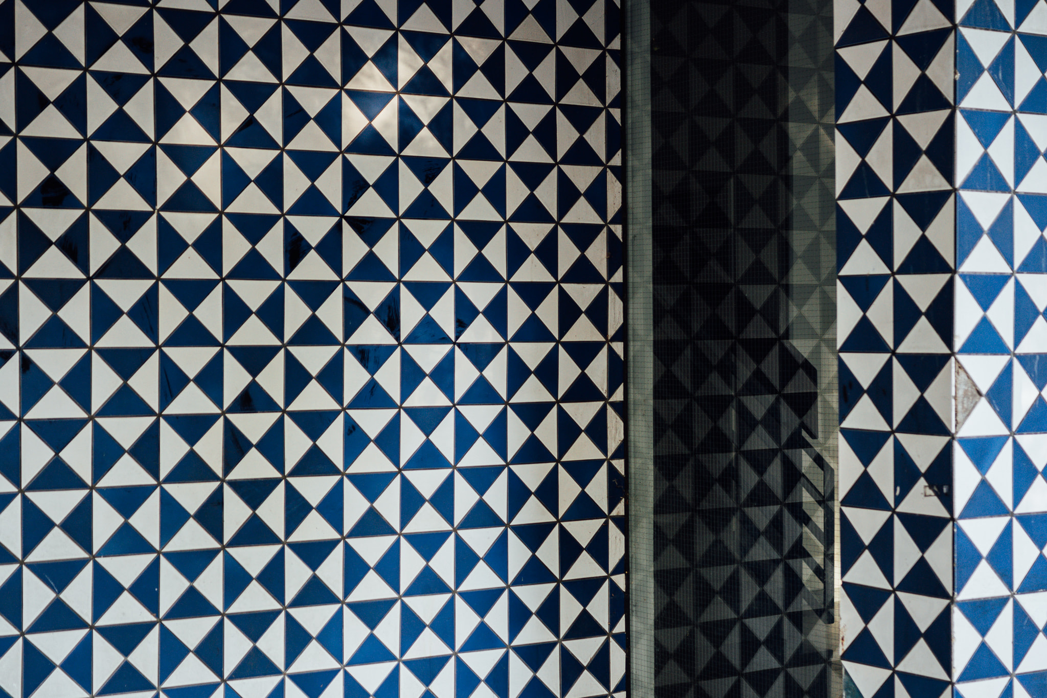 Blue and white triangular geometric tile pattern on a wall corner
