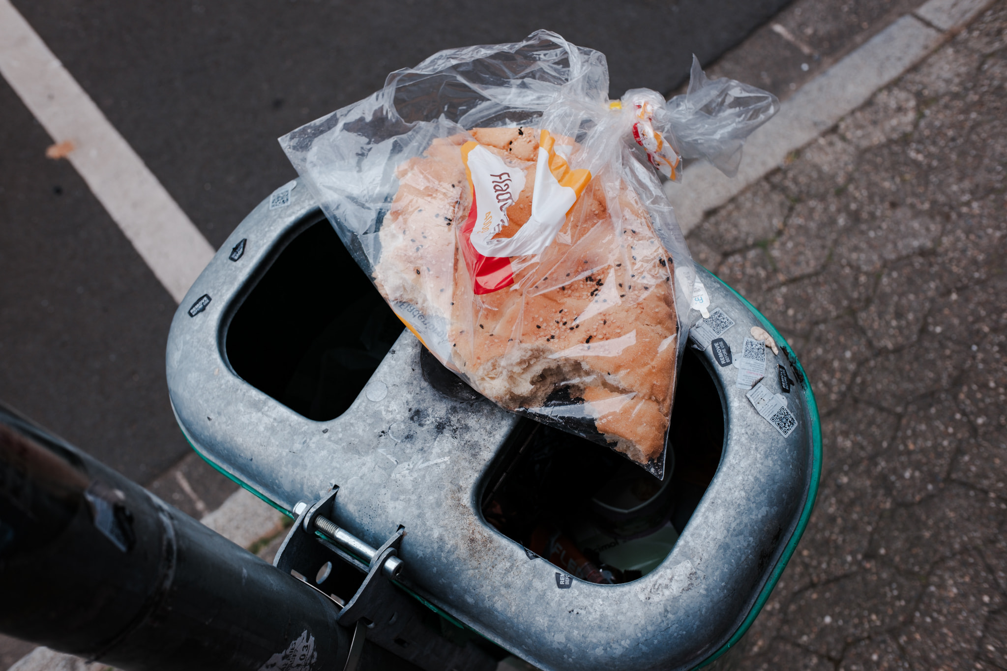 Loaf of bread in plastic bag discarded in urban trash bin