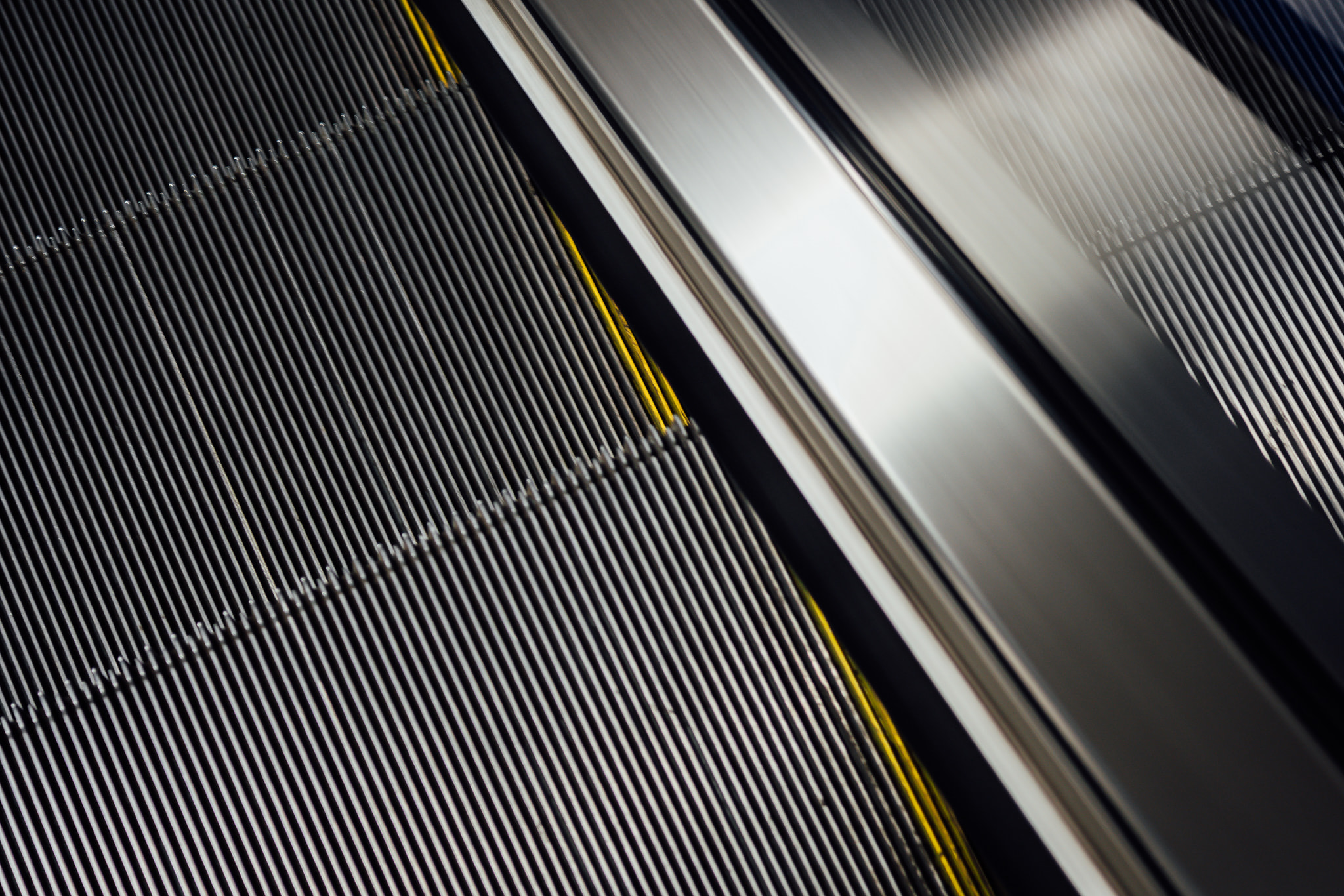 Close-up view of a moving escalator step surface and metal handrail.
