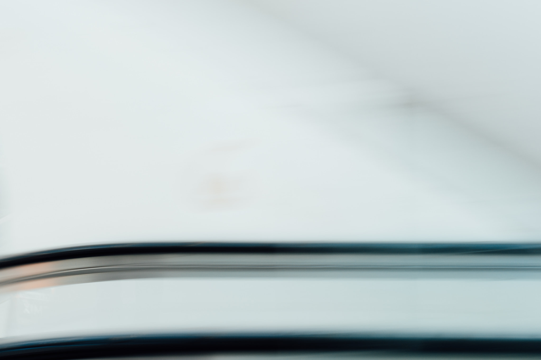 Blurred abstract escalator handrail in bright white interior