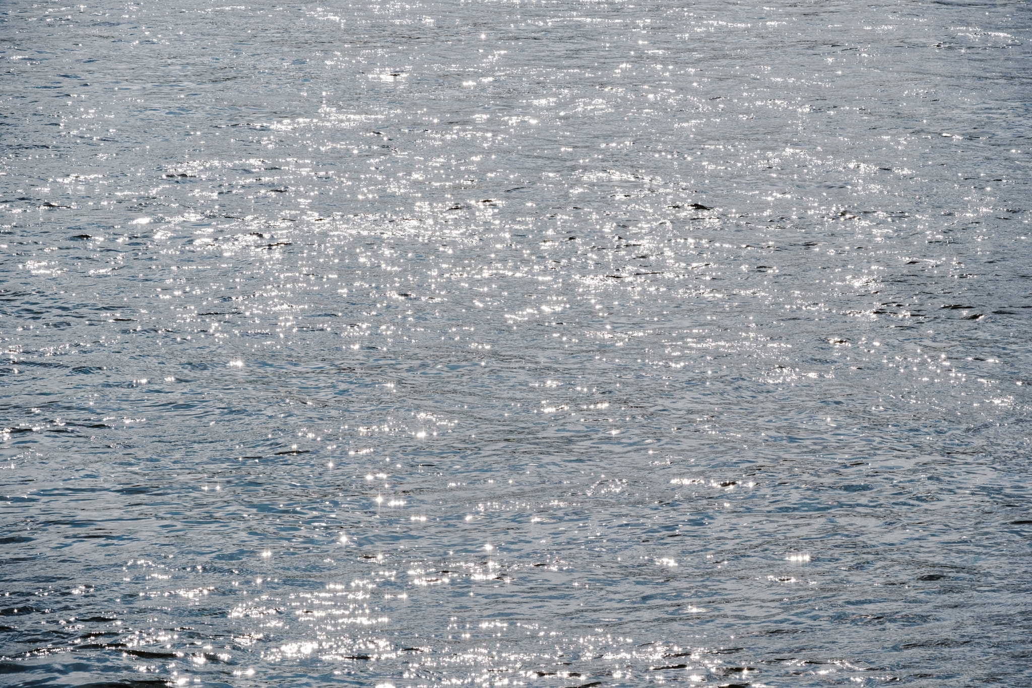 Sunlight sparkling and glittering on rippling blue water surface