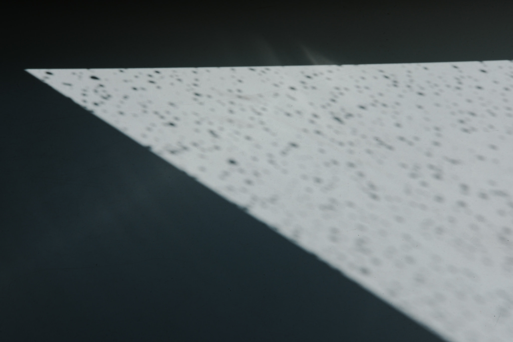 Abstract triangular white light beam with speckles on dark background