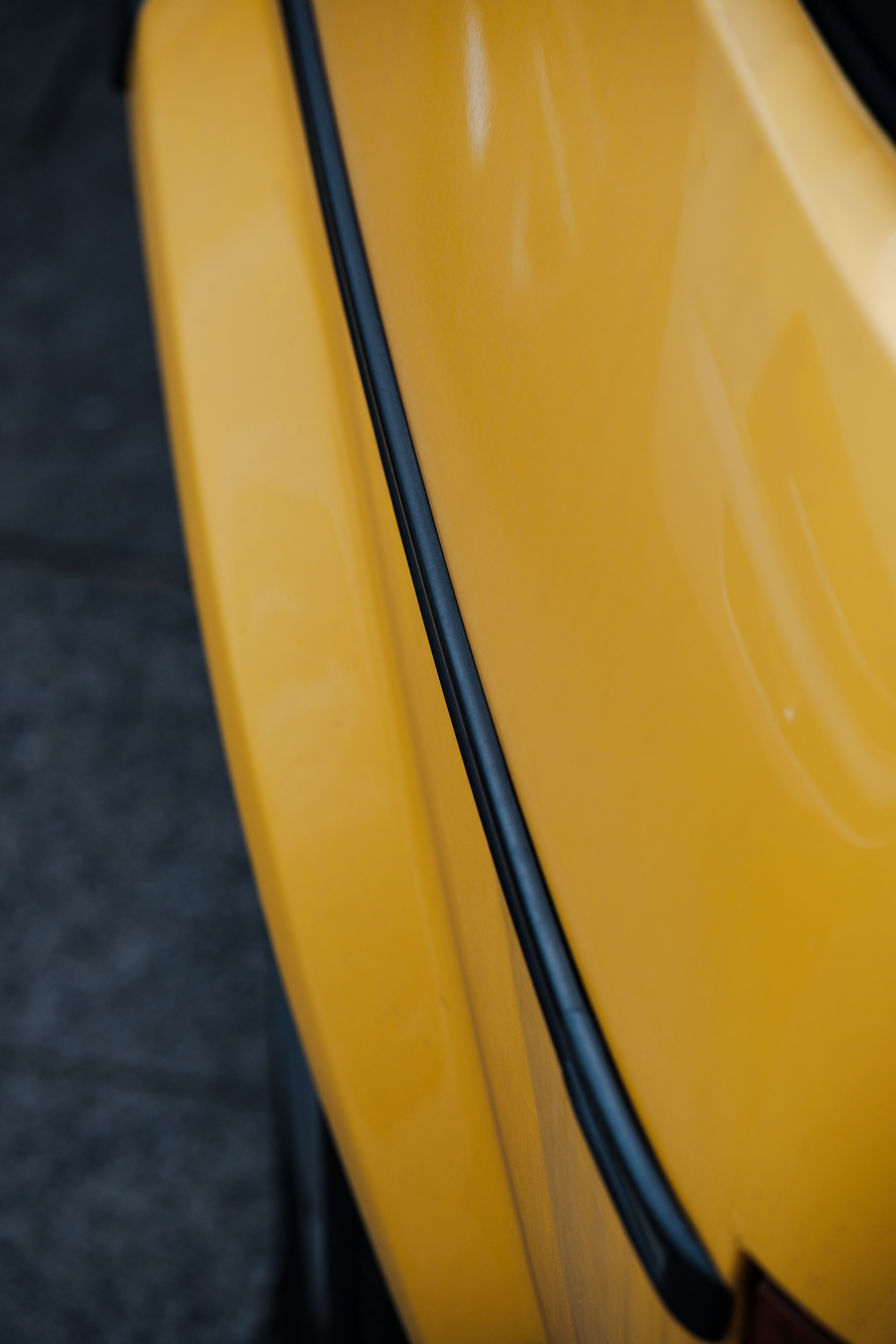 Close-up of glossy yellow car fender with black trim detail