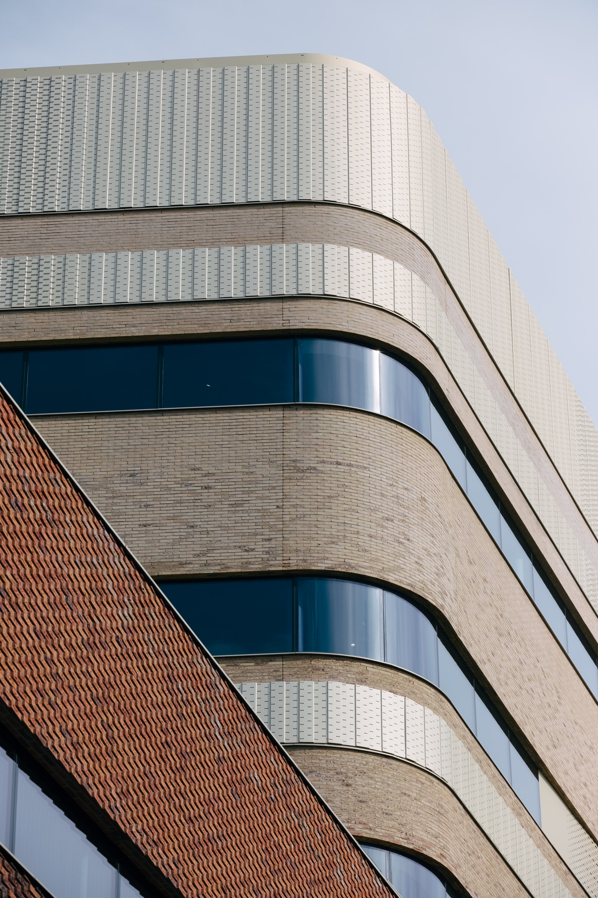 Modern curved brick building corner with glass windows and metal panels