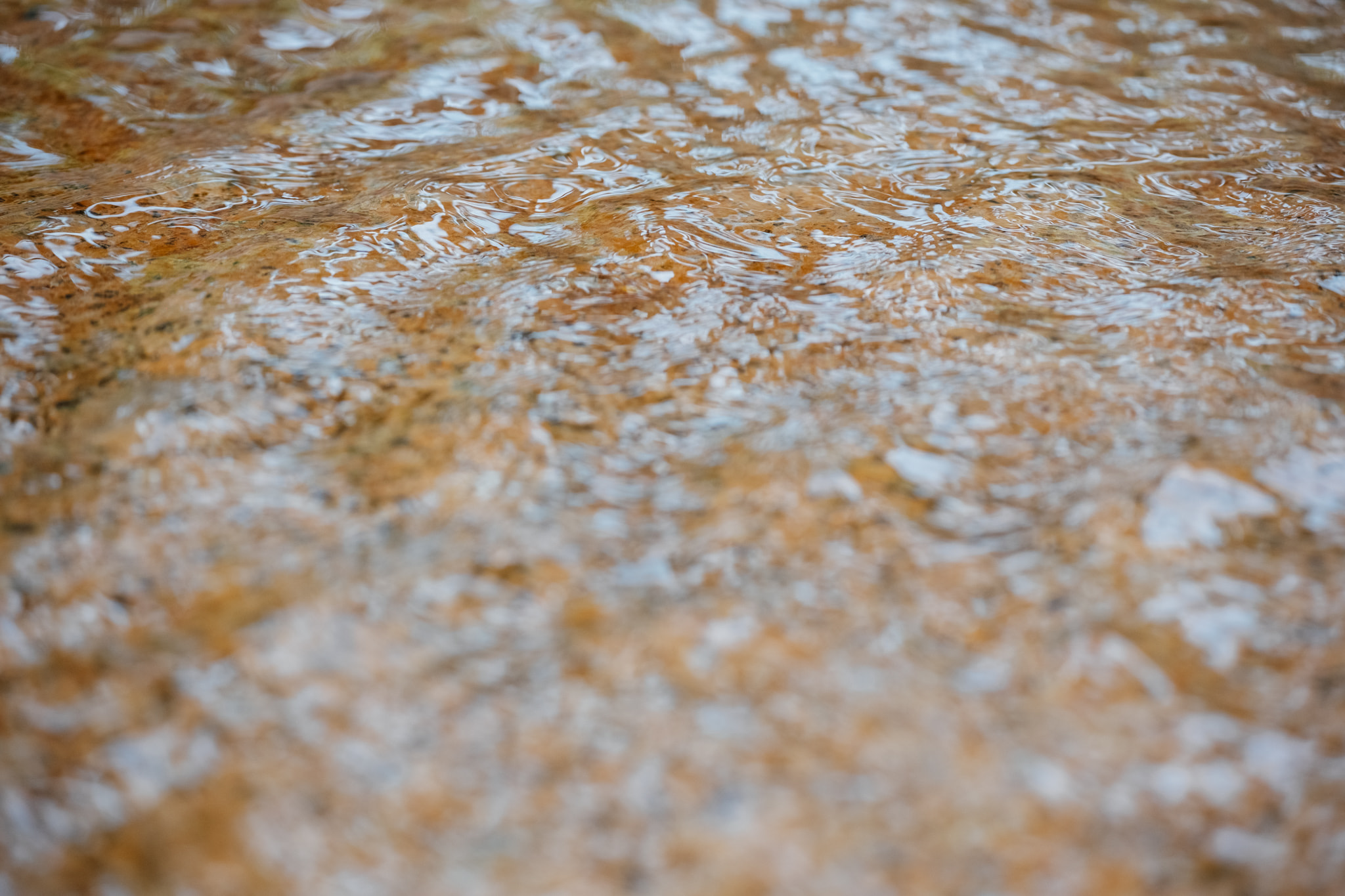 Clear shallow water rippling over brown rocky riverbed